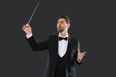 Professional conductor with baton on black background