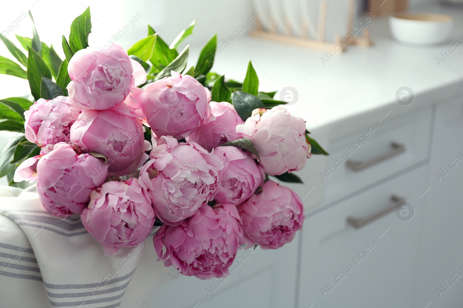 Photo of Bouquet of beautiful pink peonies on counter in kitchen