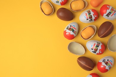 Photo of Sveti Vlas, Bulgaria - June 29, 2023: Kinder Surprise Eggs and plastic capsules on orange background, flat lay. Space for text