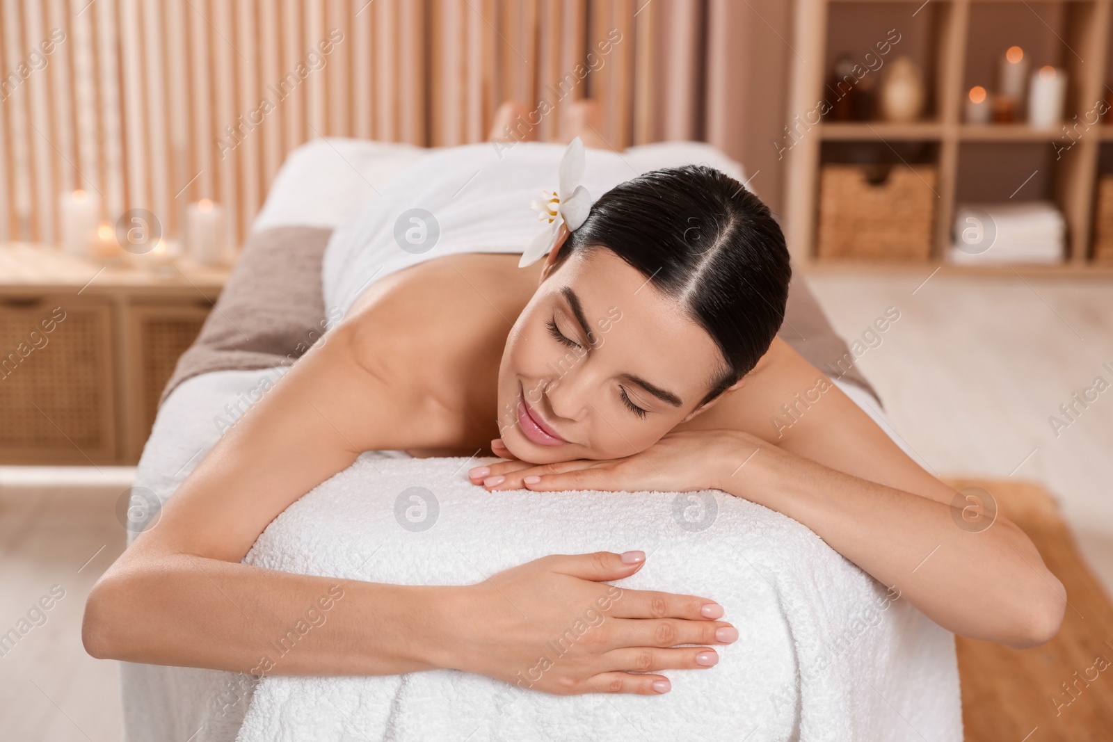 Photo of Young woman resting on massage couch in spa salon