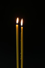 Two burning church candles on dark background