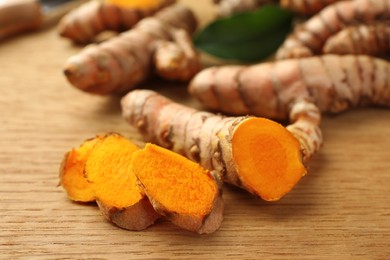 Cut turmeric roots on wooden table, closeup