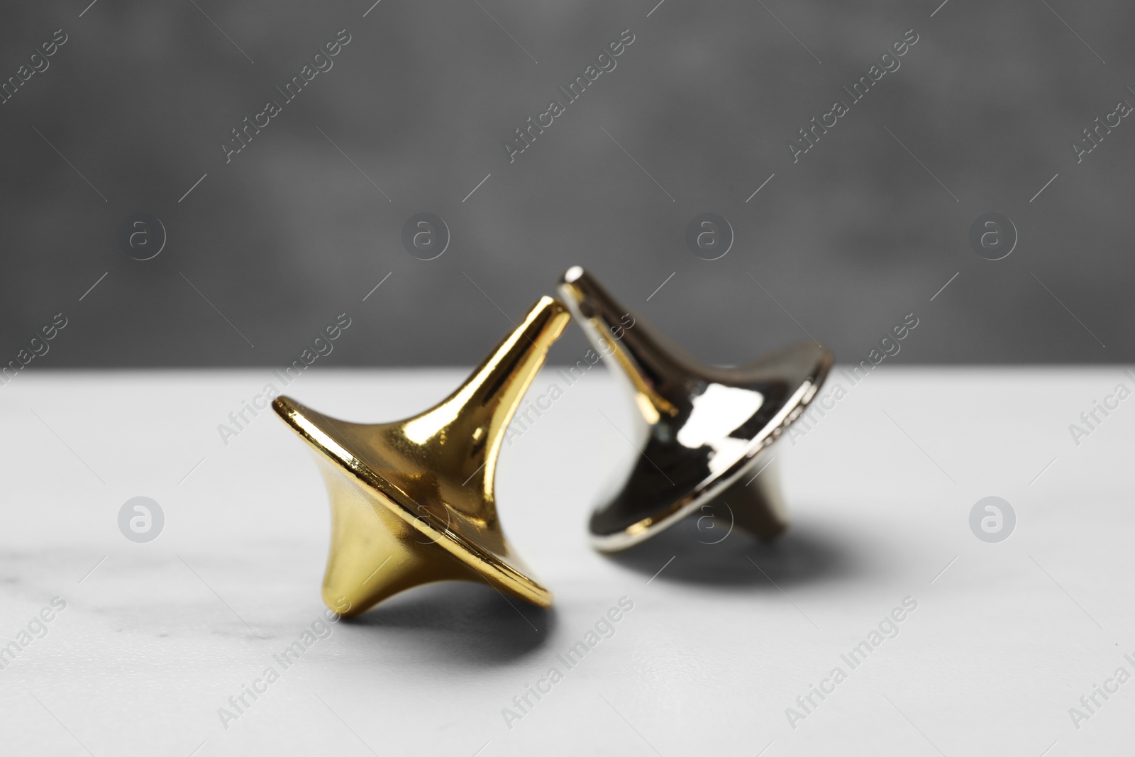 Photo of Two metal spinning tops on white table, closeup