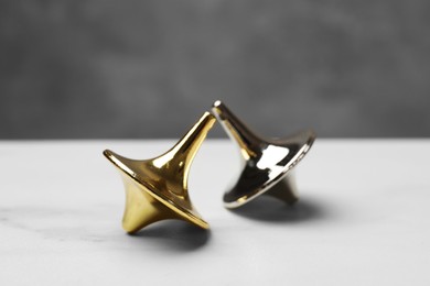 Photo of Two metal spinning tops on white table, closeup