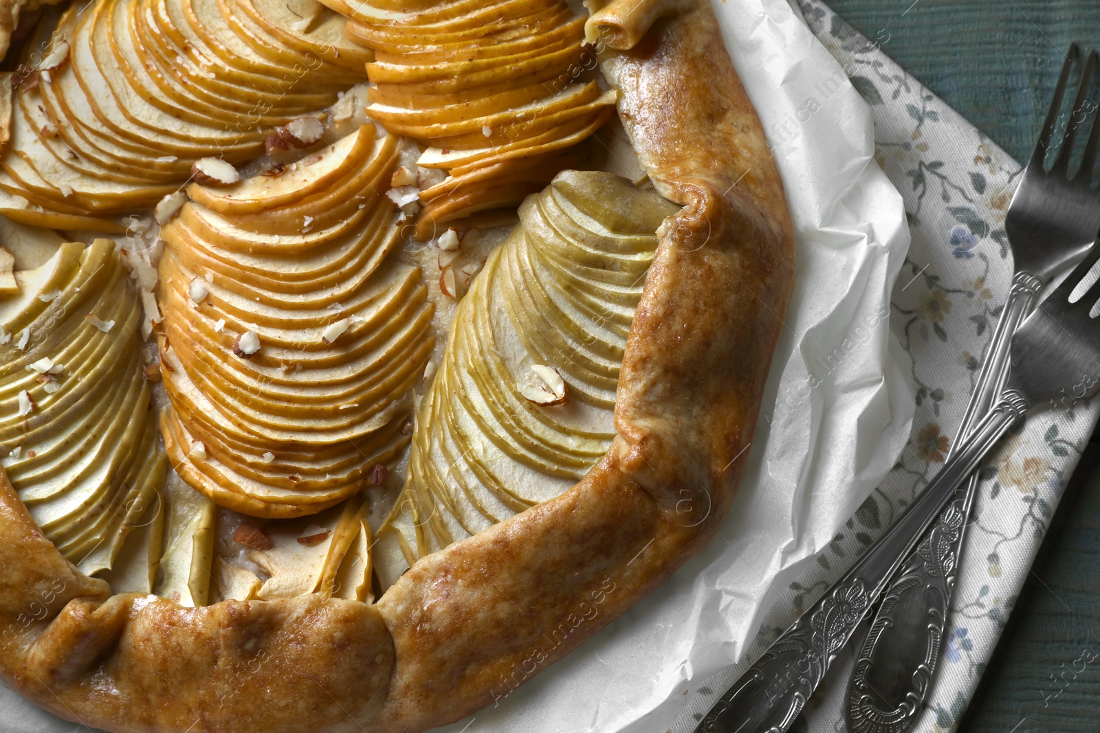 Photo of Delicious apple galette with walnuts and forks on table, top view