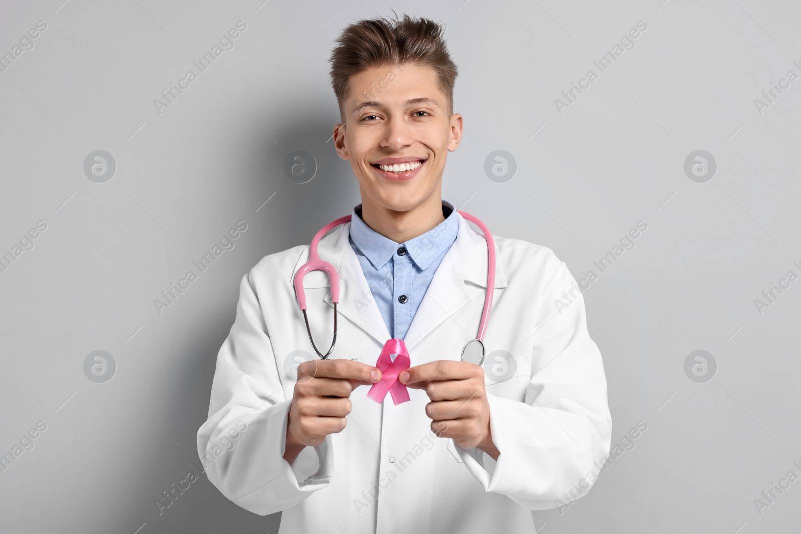 Photo of Mammologist with pink ribbon on light grey background. Breast cancer awareness