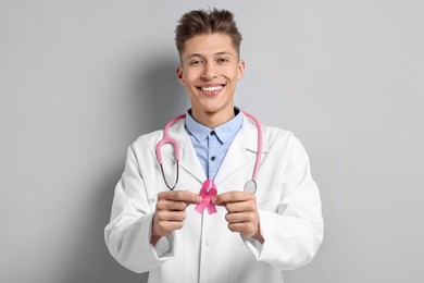 Mammologist with pink ribbon on light grey background. Breast cancer awareness