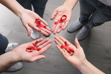 Photo of Group of people holding red awareness ribbons indoors, above view. World AIDS disease day