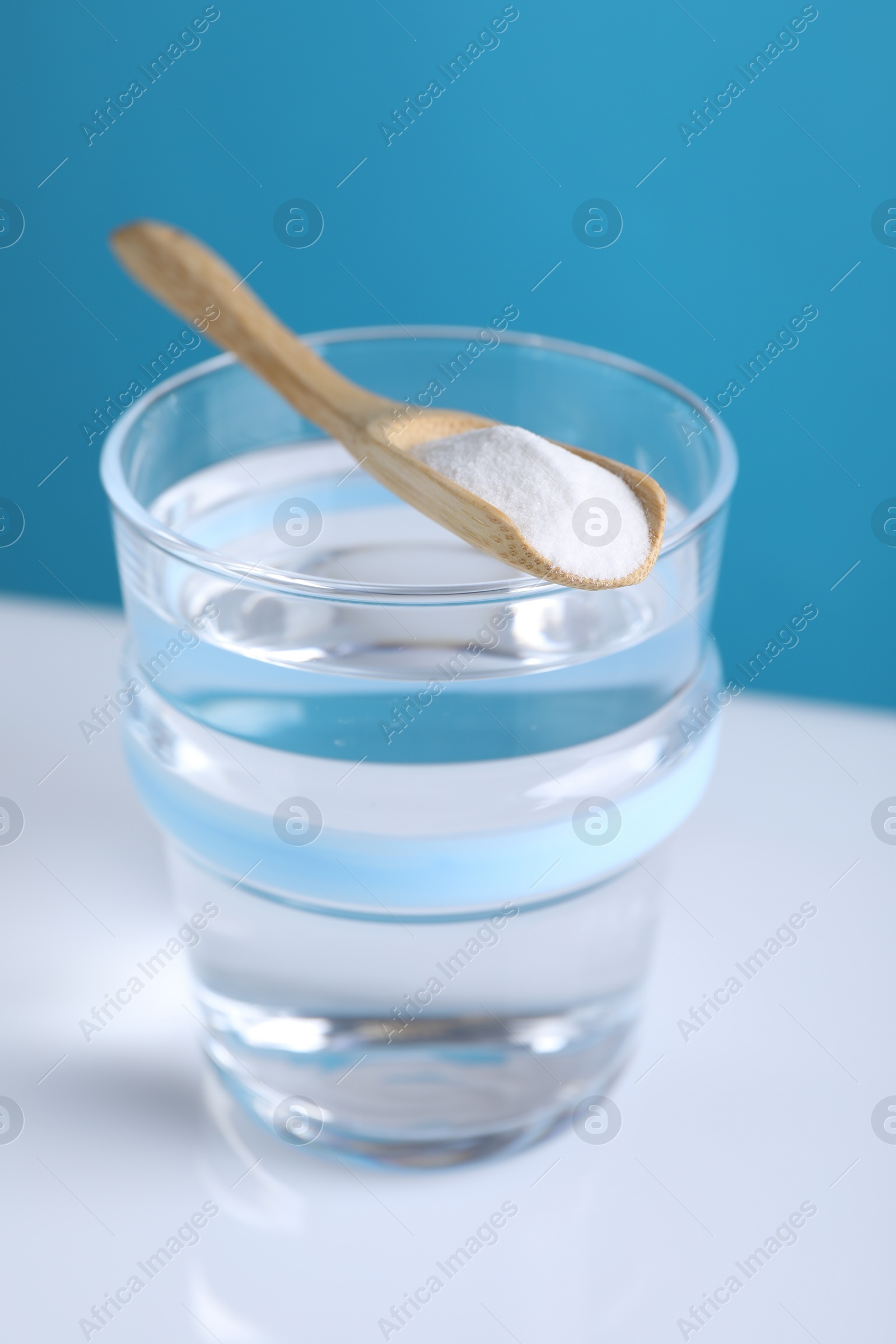 Photo of Glass of water and spoon with baking soda on color background