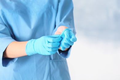 Photo of Doctor taking off medical gloves on color background. Space for text