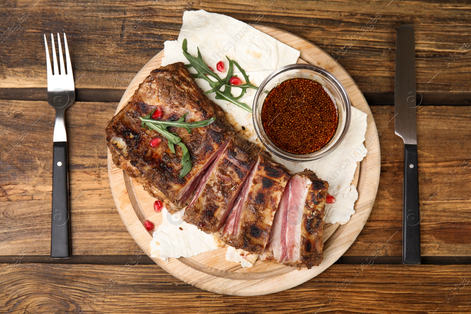 Photo of Delicious grilled ribs served on wooden table, flat lay