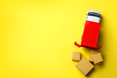 Photo of Top view of toy truck with boxes on yellow background, space for text. Logistics and wholesale concept