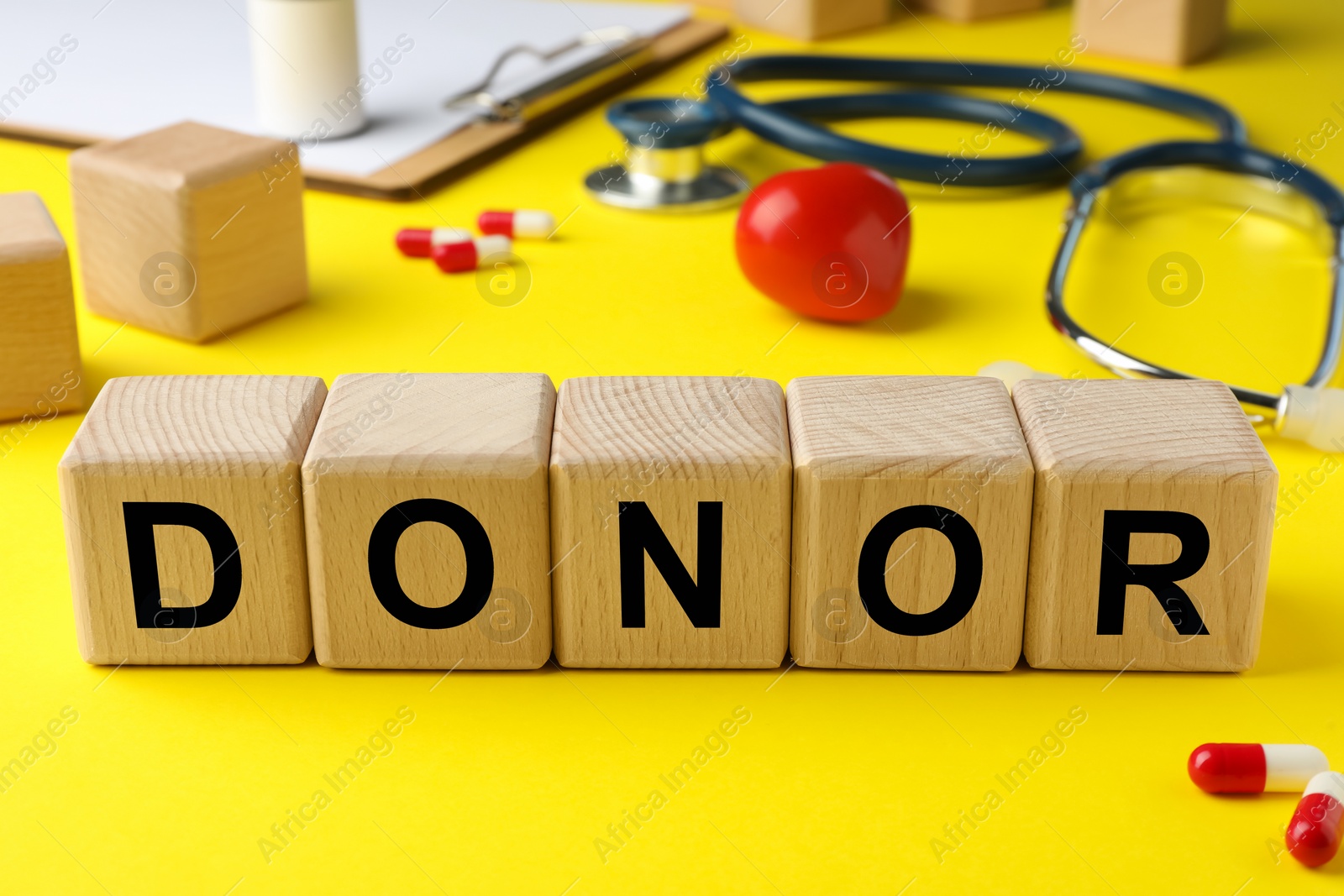 Photo of Wooden cubes with word Donor on yellow background