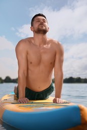 Man practicing yoga on SUP board on river