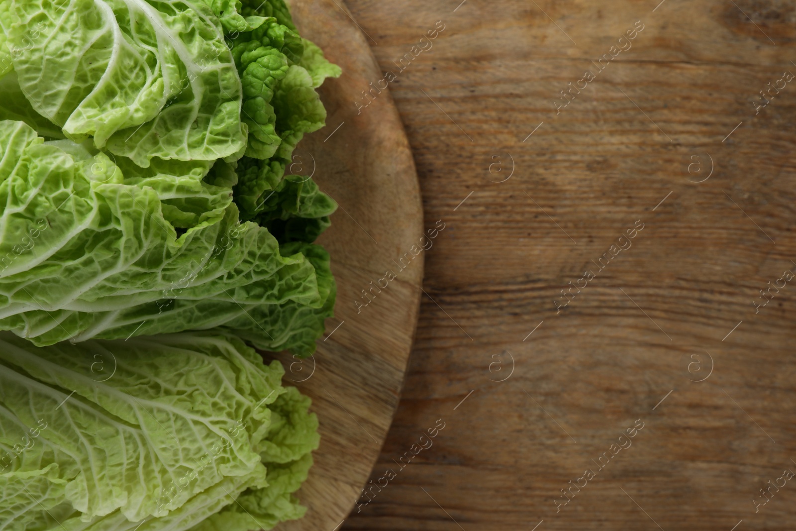 Photo of Fresh ripe leaves of Chinese cabbage on wooden table, top view. Space for text