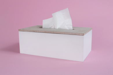 Photo of Holder with paper tissues on pink background