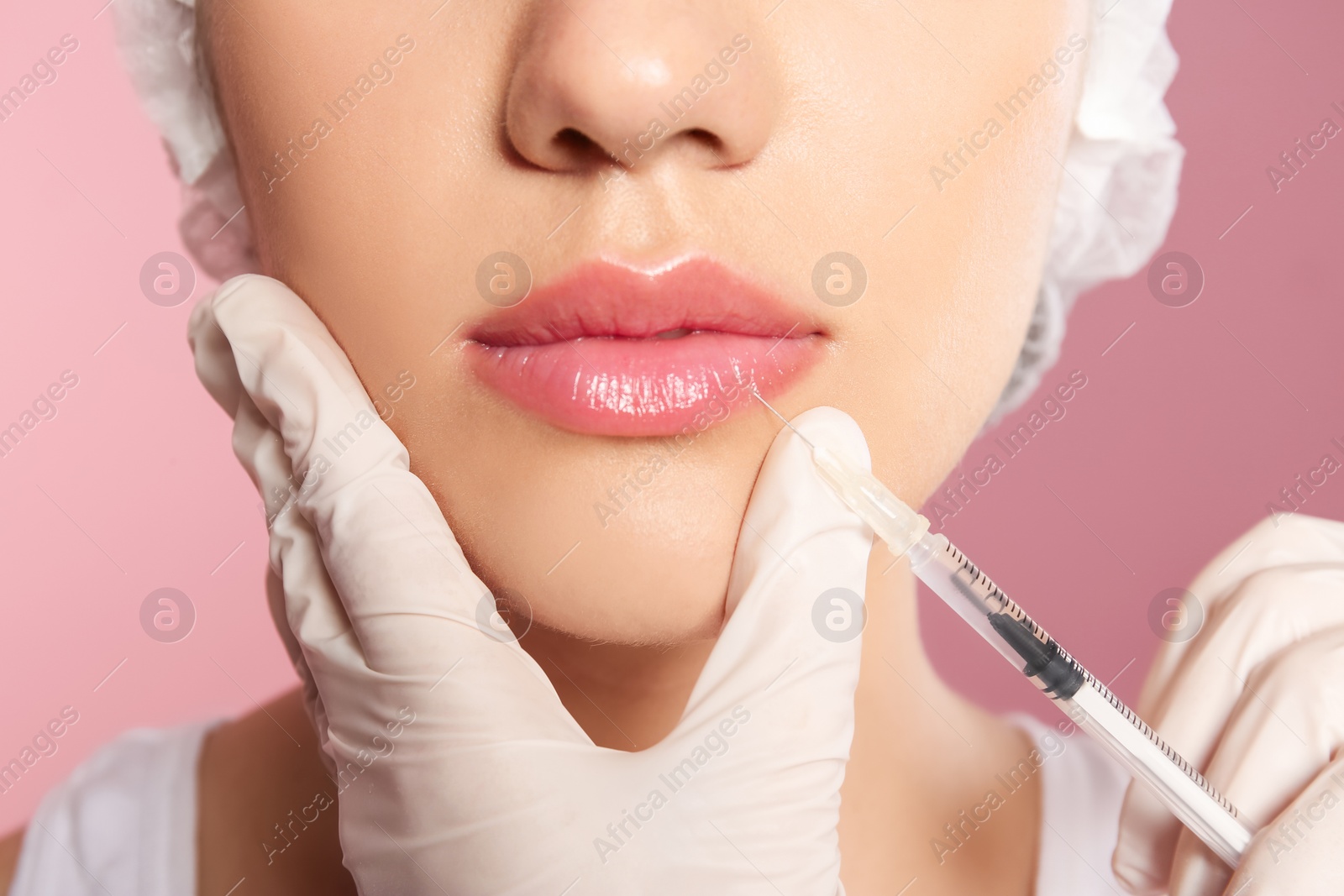 Photo of Young woman getting lip injection on color background, closeup