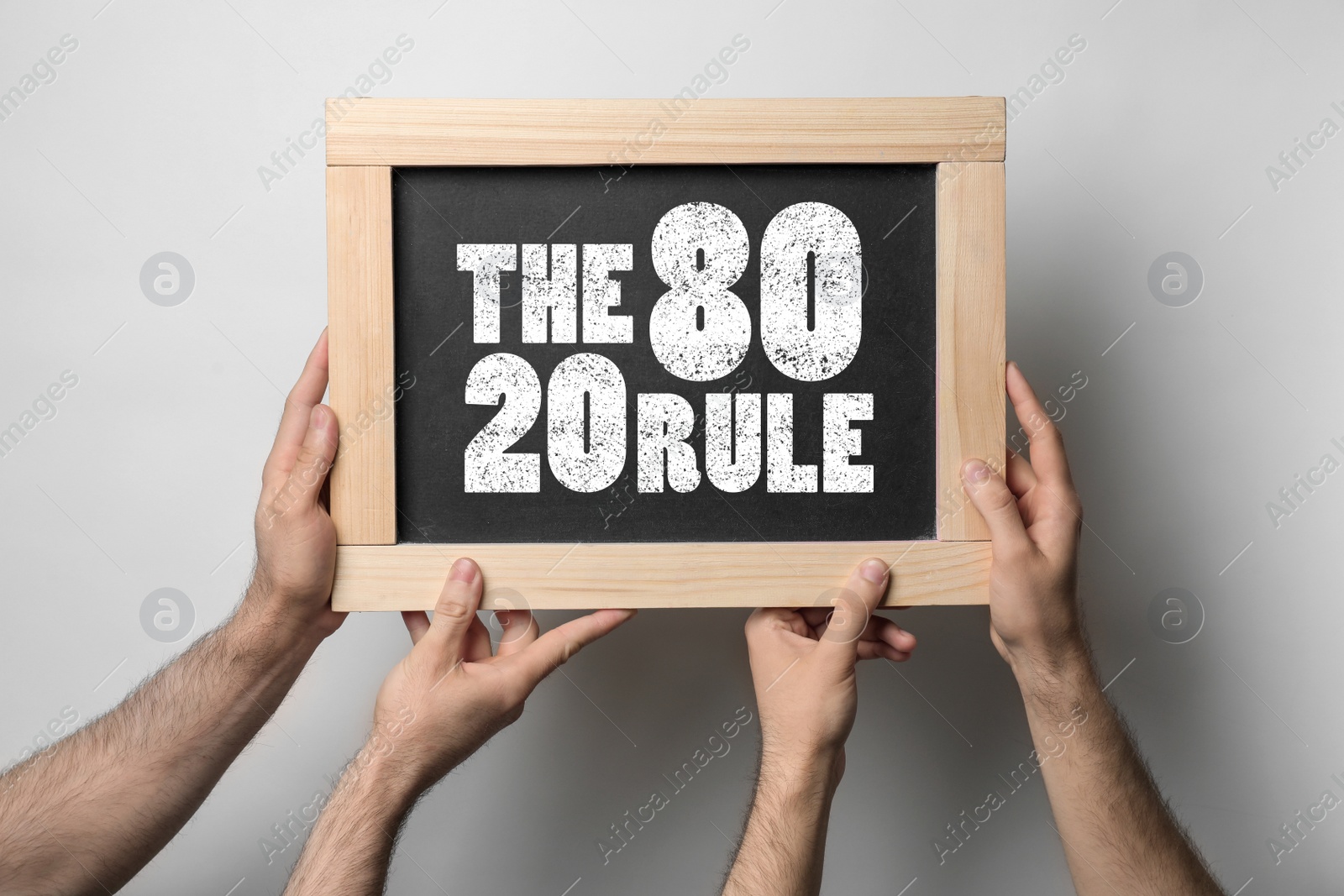 Image of Pareto principle concept. People holding blackboard with 80/20 rule representation on light background, closeup