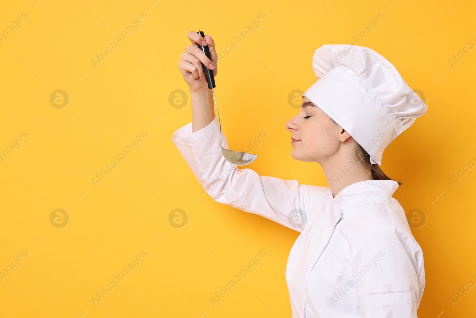 Photo of Professional chef with ladle tasting something on yellow background. Space for text