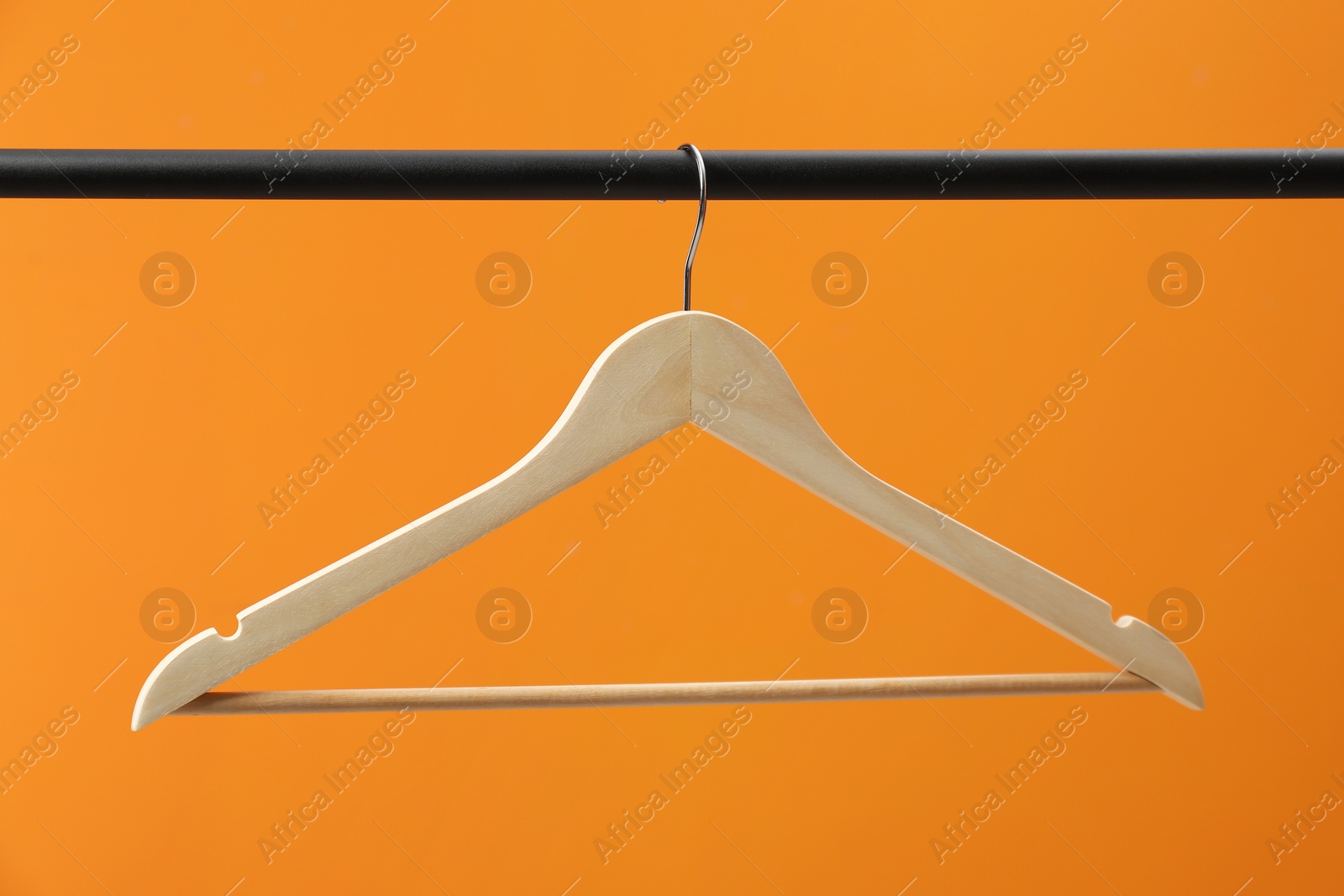 Photo of Empty clothes hanger on rack against orange background