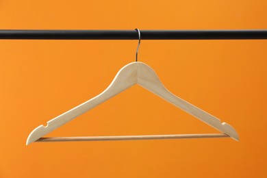 Photo of Empty clothes hanger on rack against orange background