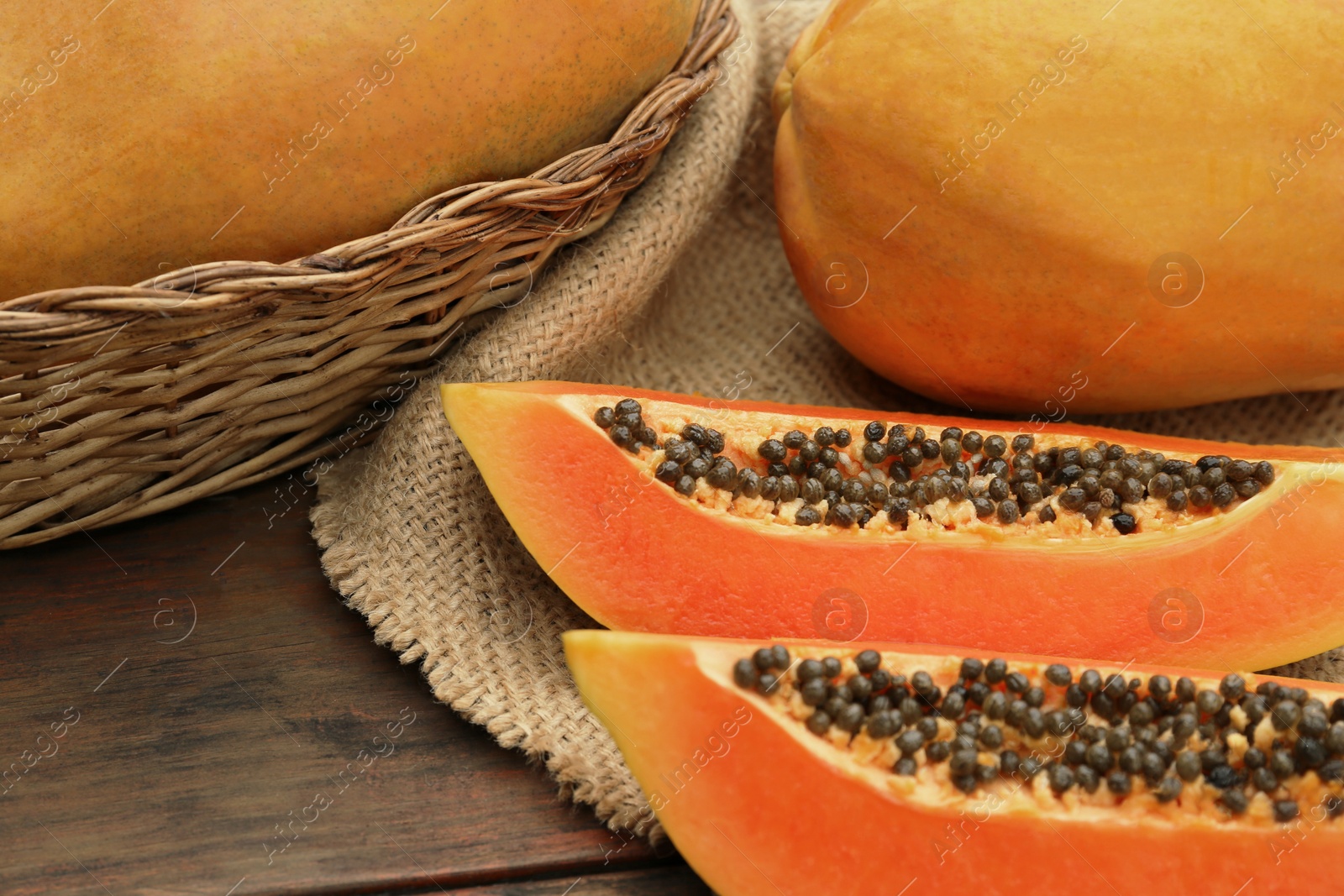 Photo of Tasty whole and cut papaya fruits on wooden table, closeup