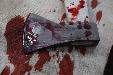 Axe with blood on wooden surface, closeup