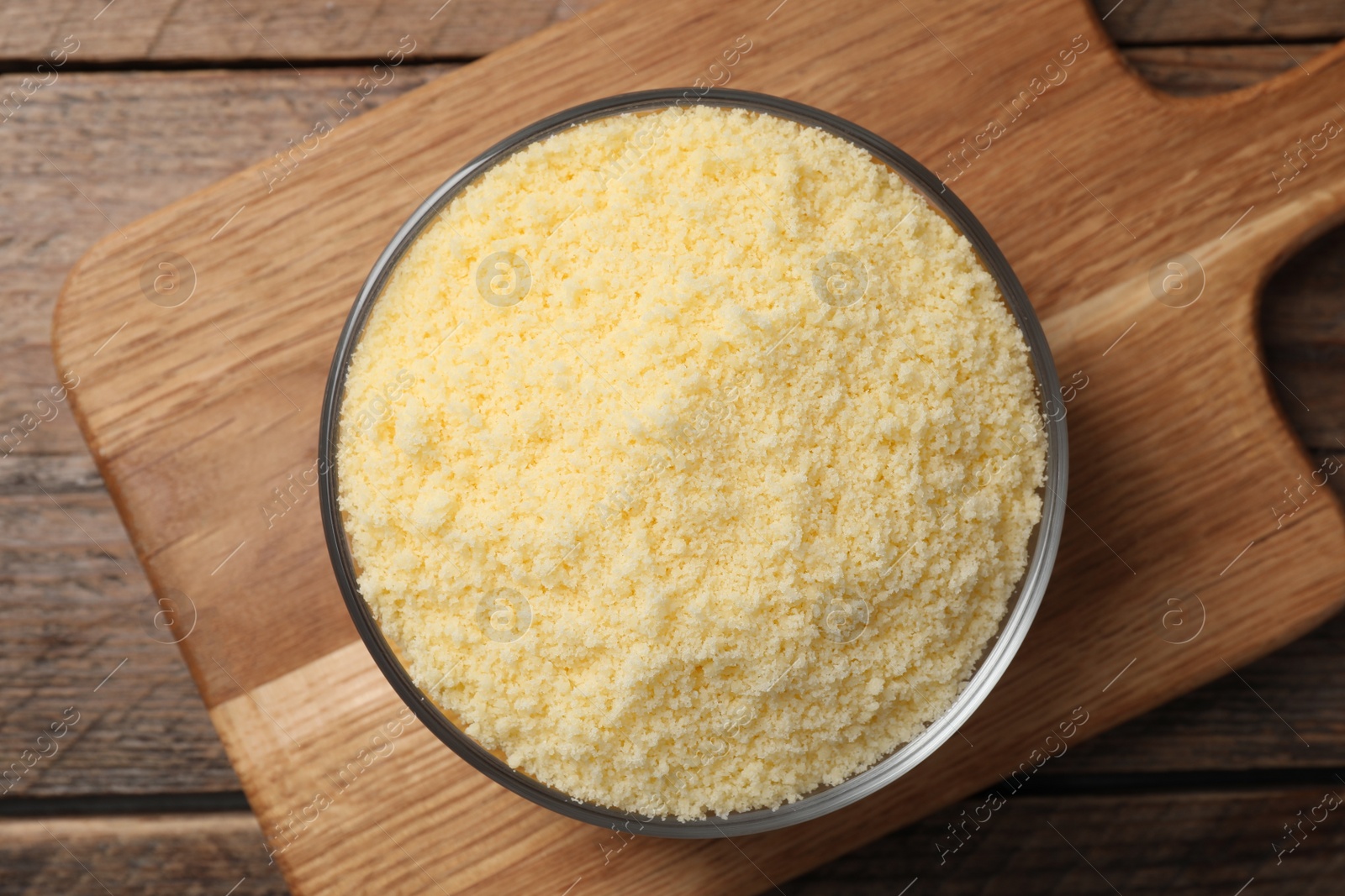 Photo of Glass bowl with grated parmesan cheese on wooden table, top view