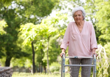 Photo of Elderly woman with walking frame outdoors. Medical help