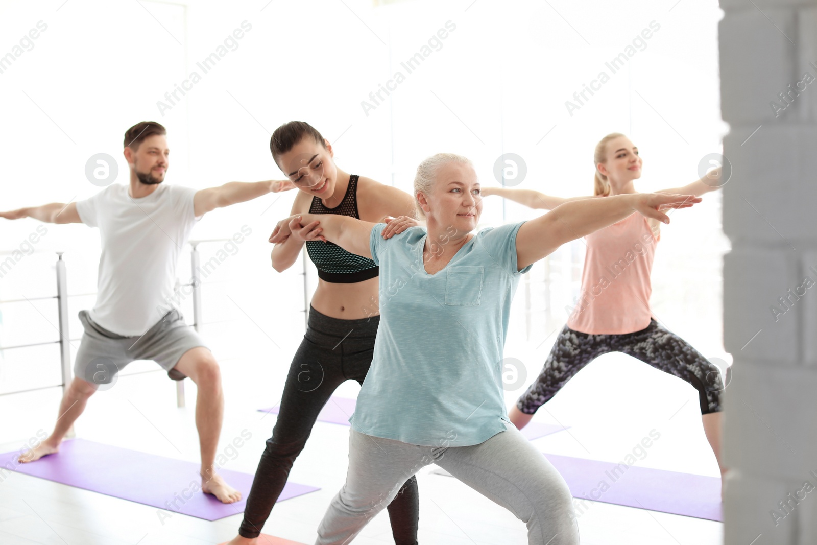 Photo of Group of people in sportswear practicing yoga indoors