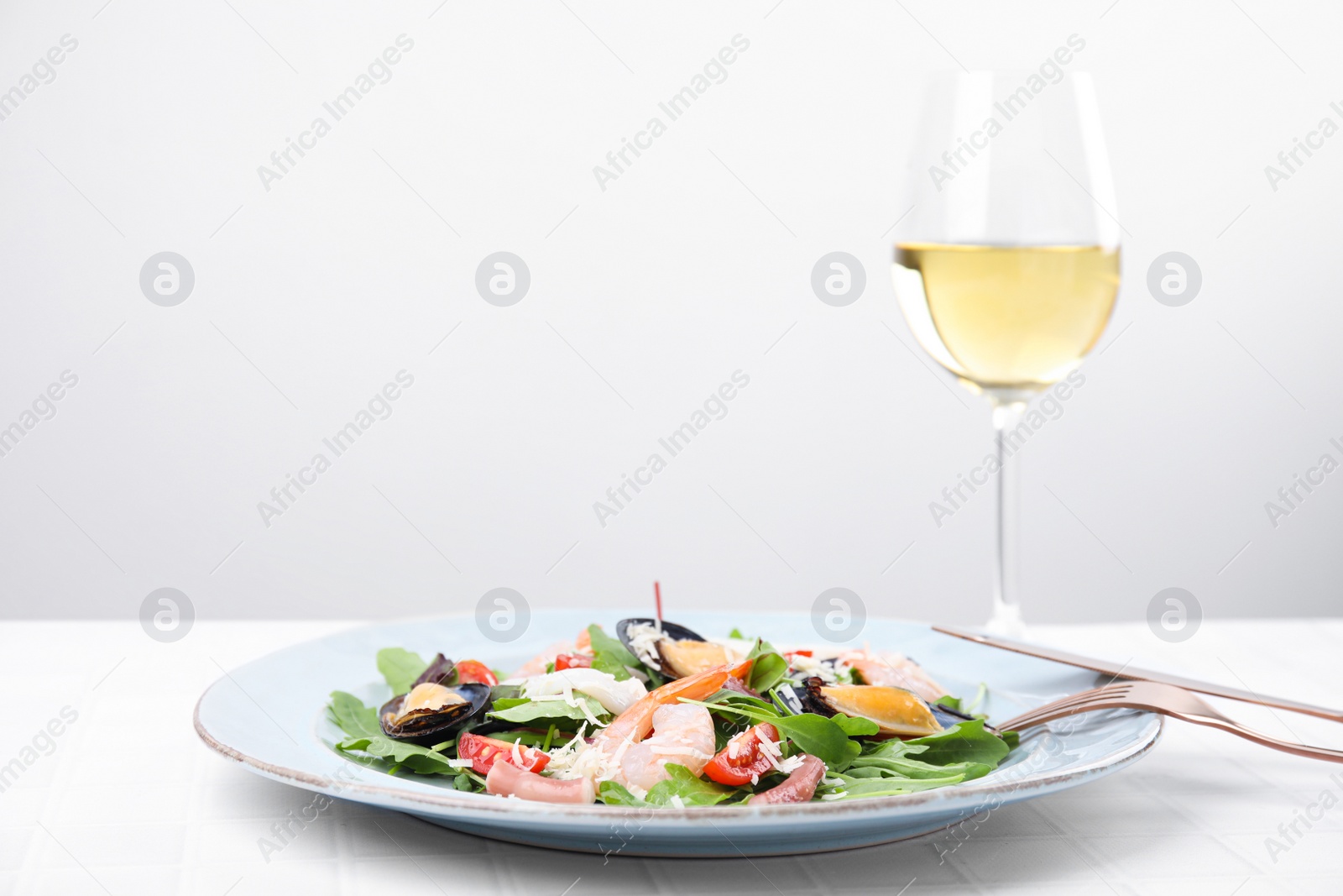 Photo of Plate of delicious salad with seafood on white tiled table