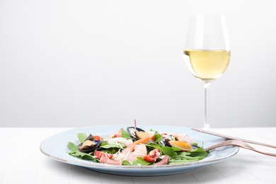 Plate of delicious salad with seafood on white tiled table