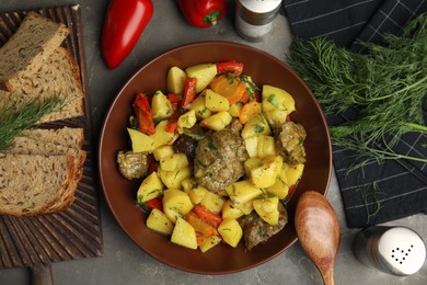 Photo of Tasty cooked dish with potatoes in earthenware served on grey table, flat lay