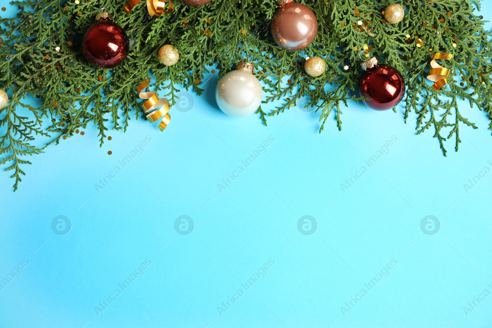 Photo of Fir tree branches with Christmas decoration on light blue background, flat lay. Space for text