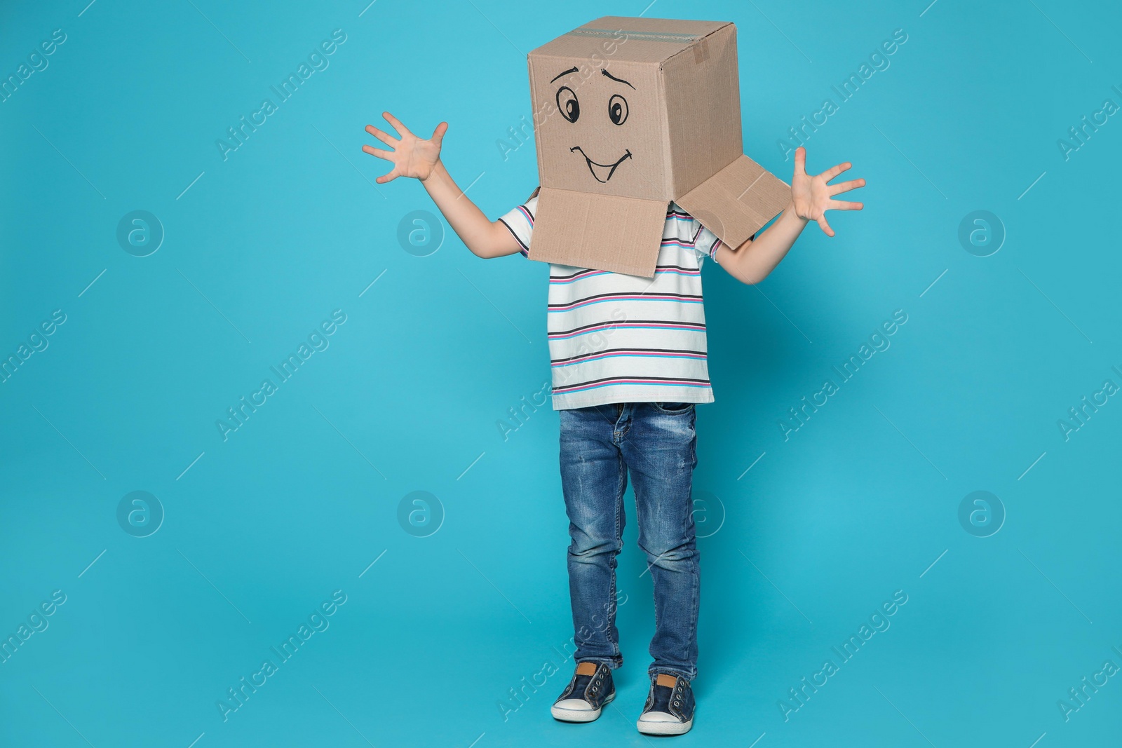 Photo of Cute little child wearing cardboard box with smiling face on color background