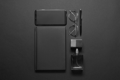 Flat lay composition with male accessories and smartphone on black background