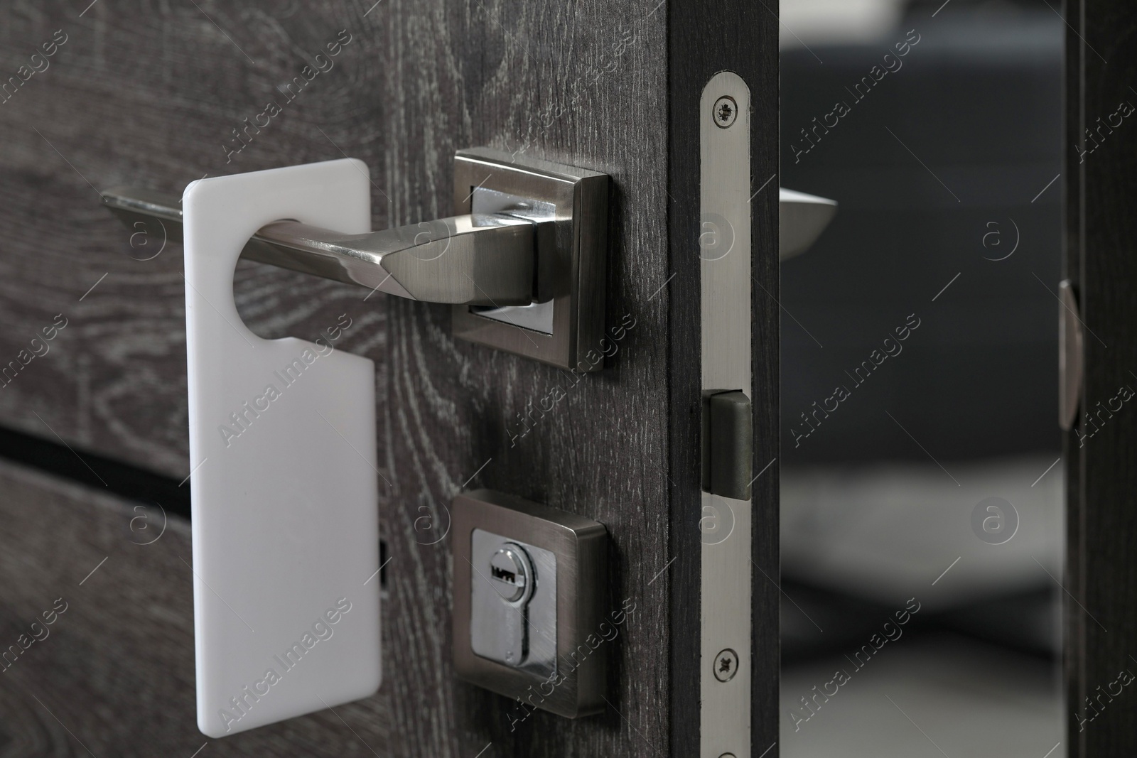 Photo of Wooden door with blank hanger on metal handle, closeup