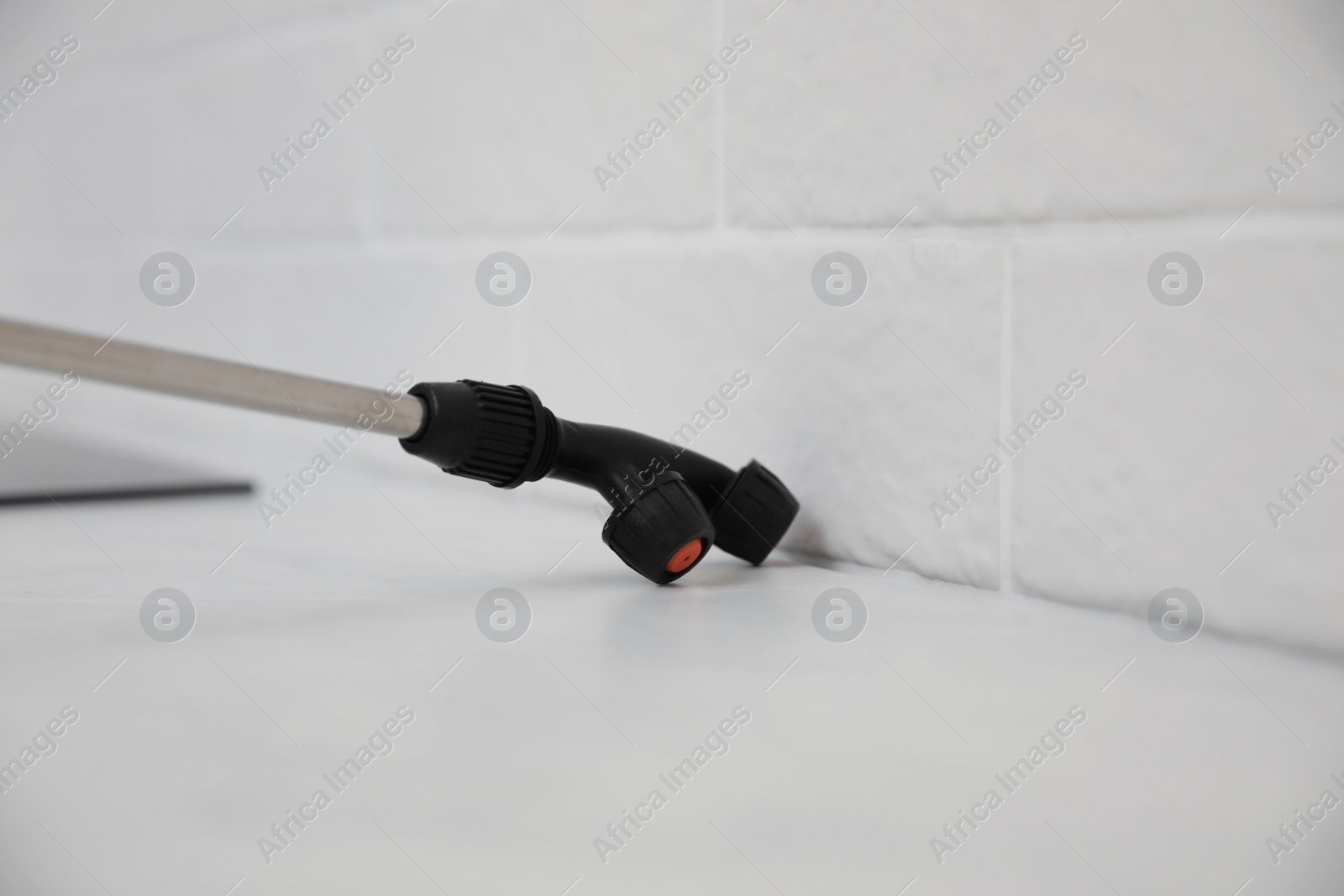 Photo of Spraying pesticide on white table indoors, closeup. Pest control service