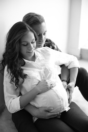 Pregnant woman with her husband indoors, black and white effect