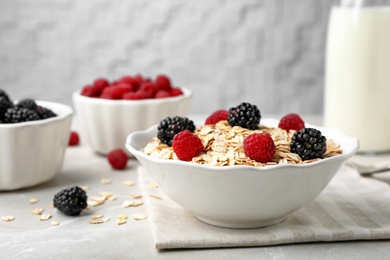 Photo of Bowl with rolled oat and berries on light table. Whole grain cereal for breakfast