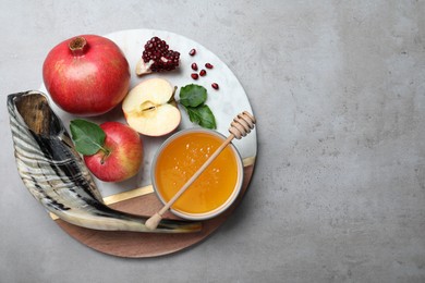 Photo of Honey, pomegranate, apples and shofar on grey table, top view. Rosh Hashana holiday
