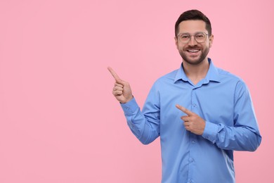 Photo of Special promotion. Smiling man pointing at something on pink background. Space for text
