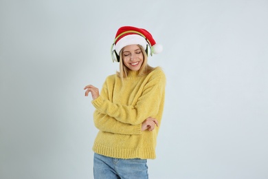 Photo of Happy woman with headphones on light grey background. Christmas music