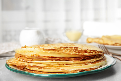 Photo of Stack of fresh thin pancakes on light grey marble table