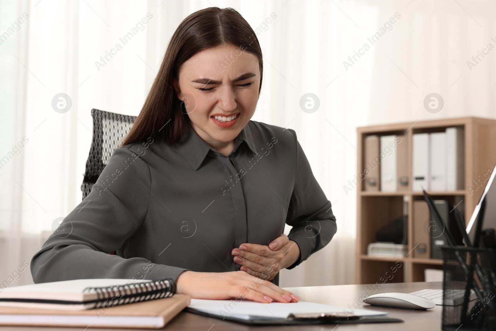 Photo of Woman having heart attack at table in office