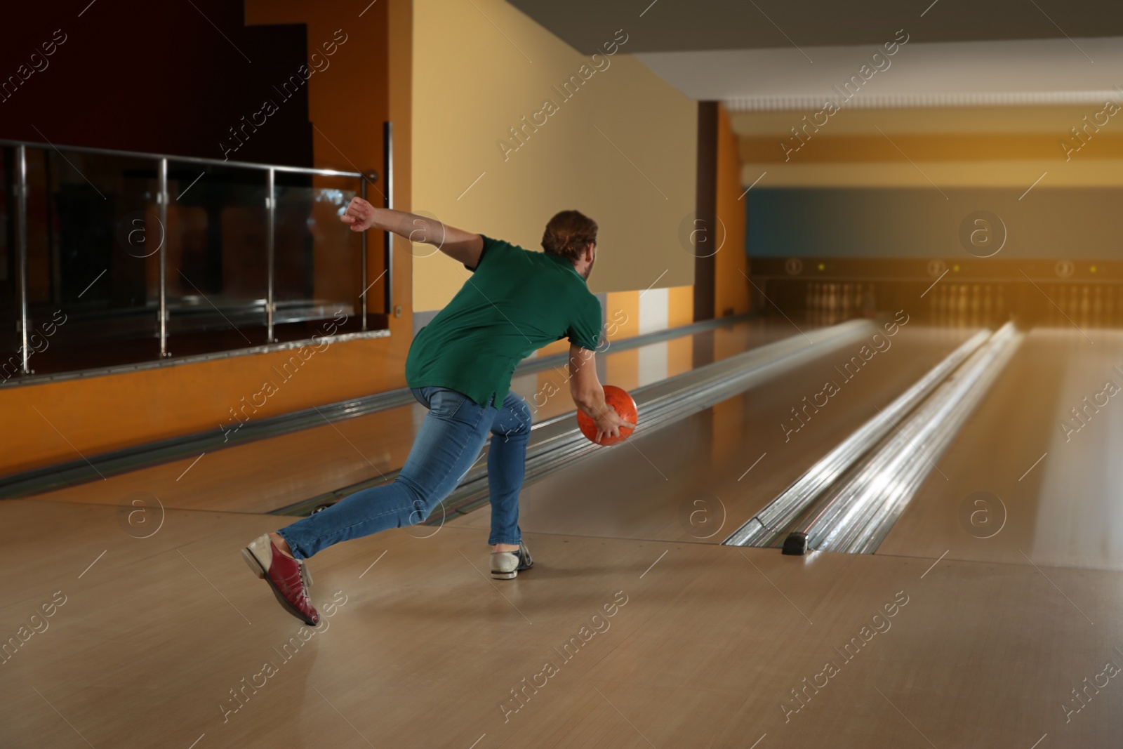 Photo of Young man throwing ball in bowling club