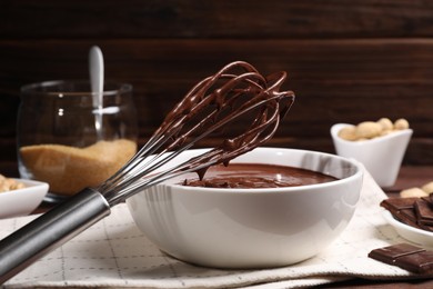 Photo of Bowl and whisk with chocolate cream on table