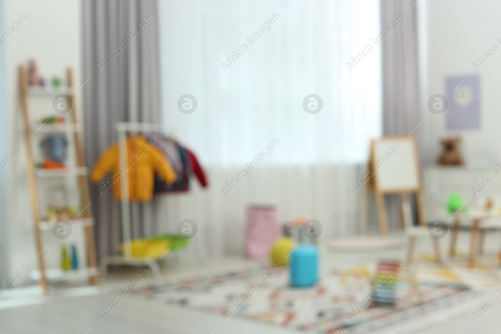 Photo of Blurred view of child`s playroom with different toys and furniture. Stylish kindergarten interior