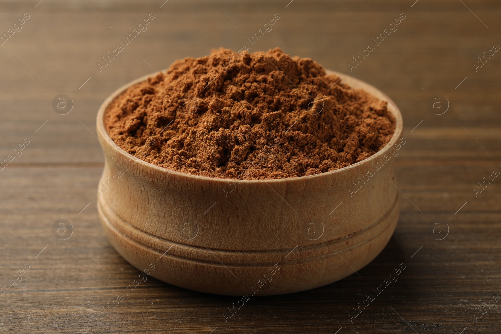 Photo of Aromatic cinnamon powder on wooden table, closeup