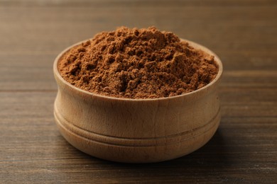 Photo of Aromatic cinnamon powder on wooden table, closeup